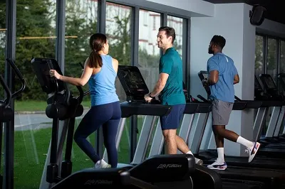 Three Members running on the window facing treadmills.