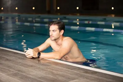 A man swimming as the afternoon sun beams in the pool