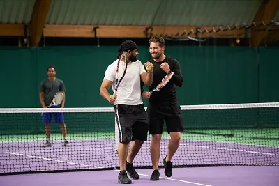 Three Men playing tennis on an indoor Court.