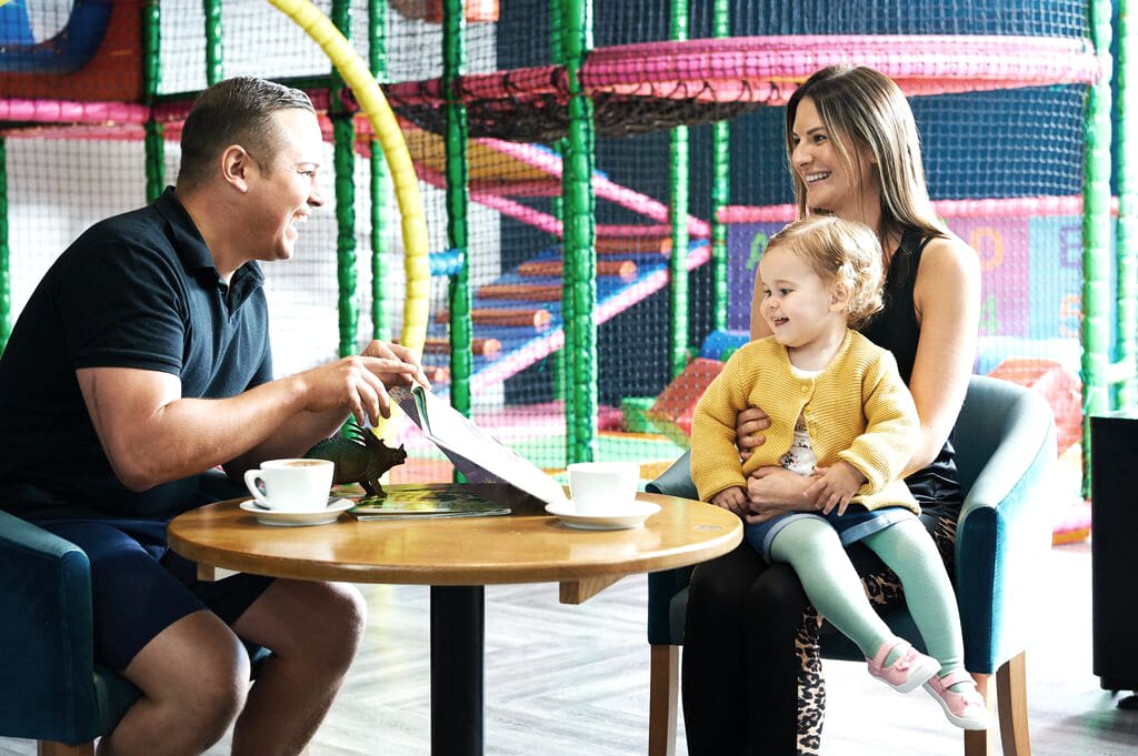 Family sit together in the soft play area at David Lloyd Clubs