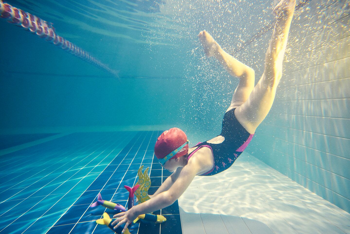 Girl diving for pool toys as part of the Swim stars programme