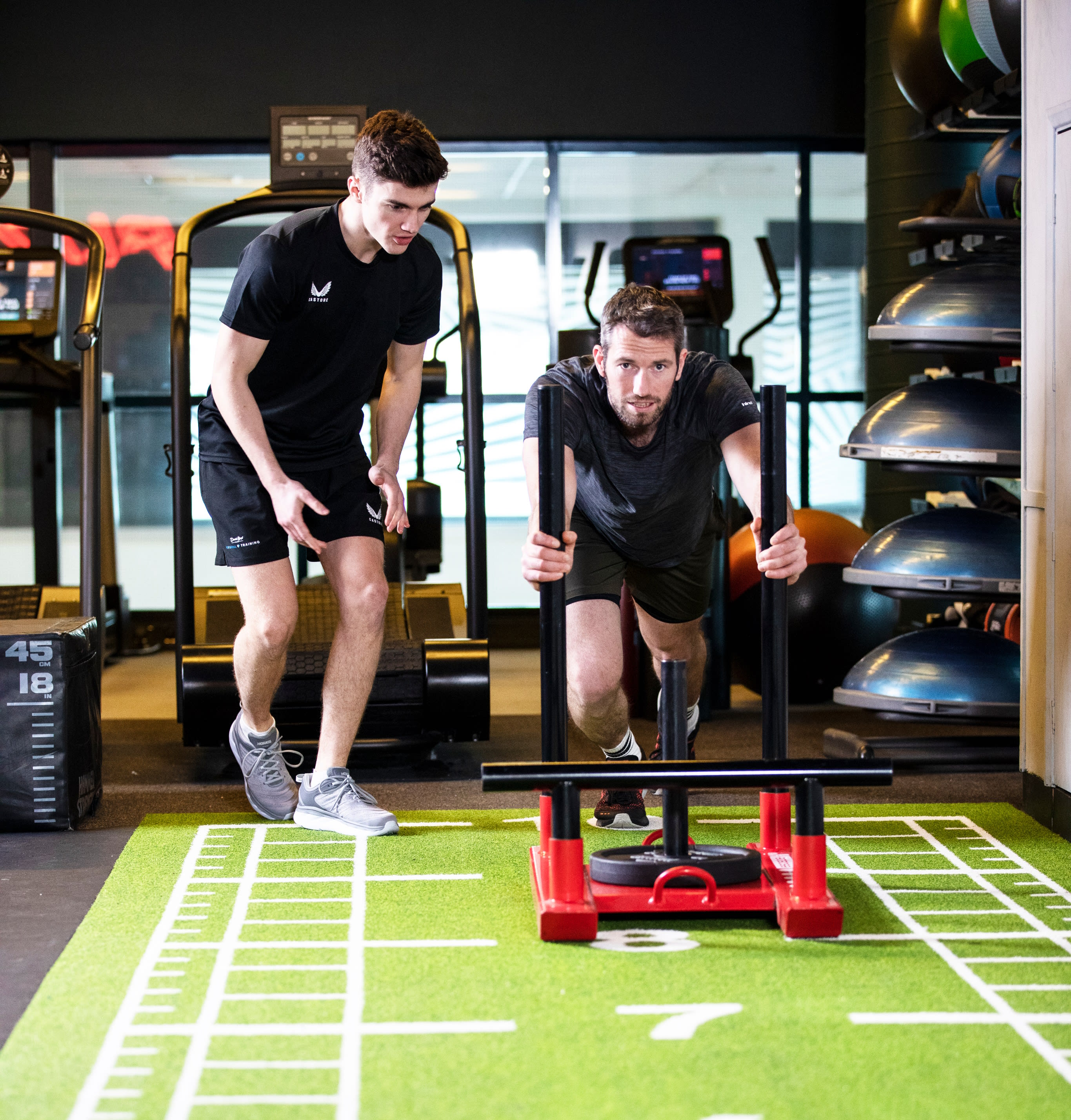 Man pushing weights with personal trainer